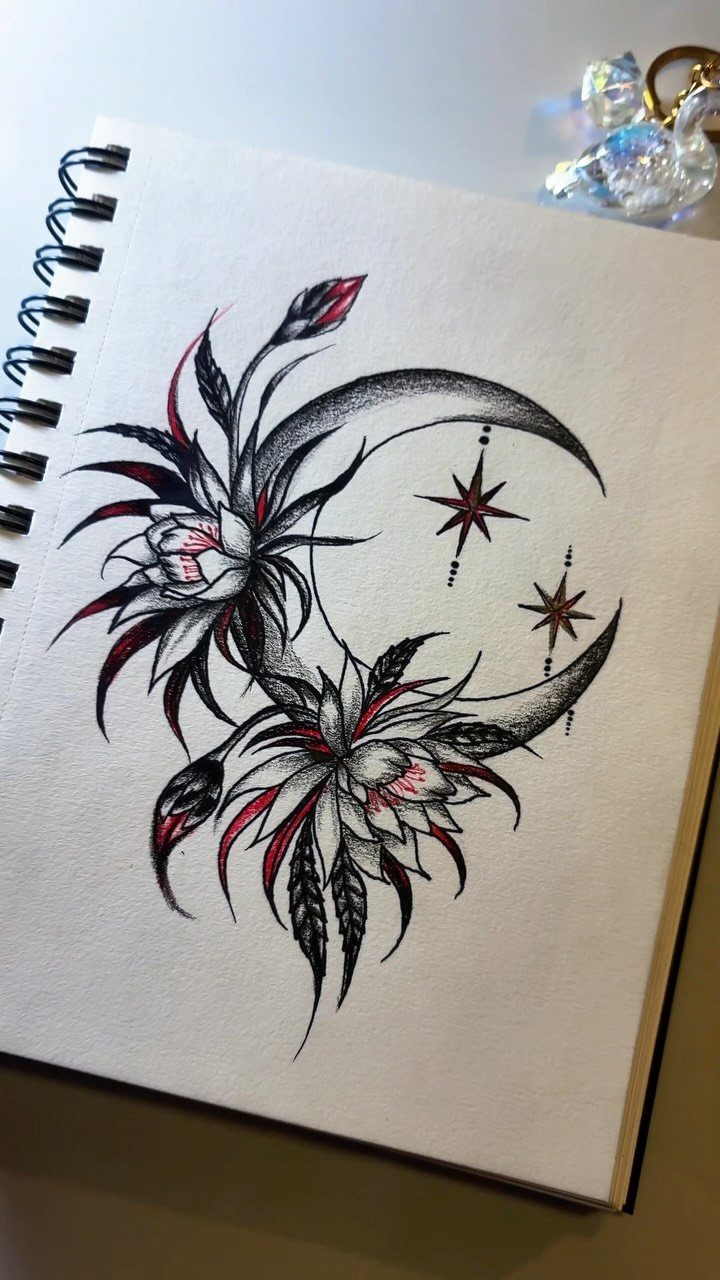 Crescent moon and stylized flowers drawing in a spiral notebook with red accents.