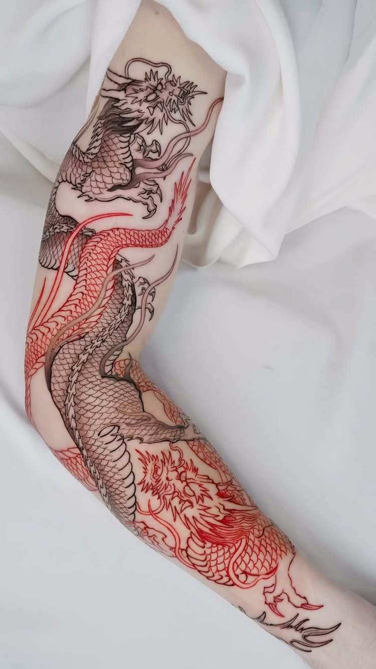 Two Asian style dragons tattooed in red and black ink on an arm.