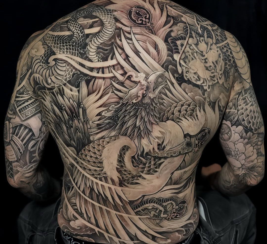 Full back tattoo of a phoenix and dragon in black and grey ink