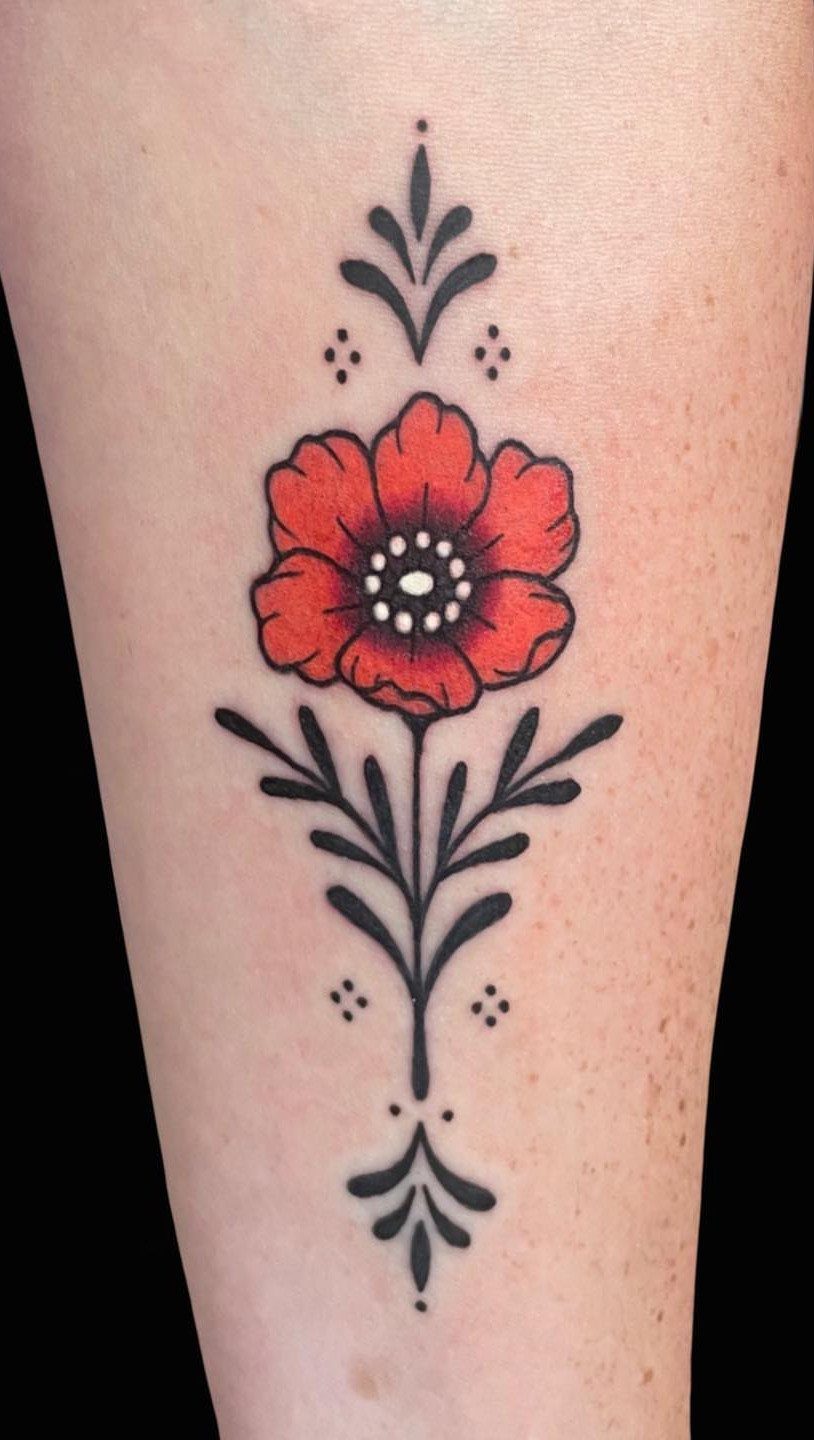 Red poppy flower tattoo with symmetrical black decorative foliage on human skin