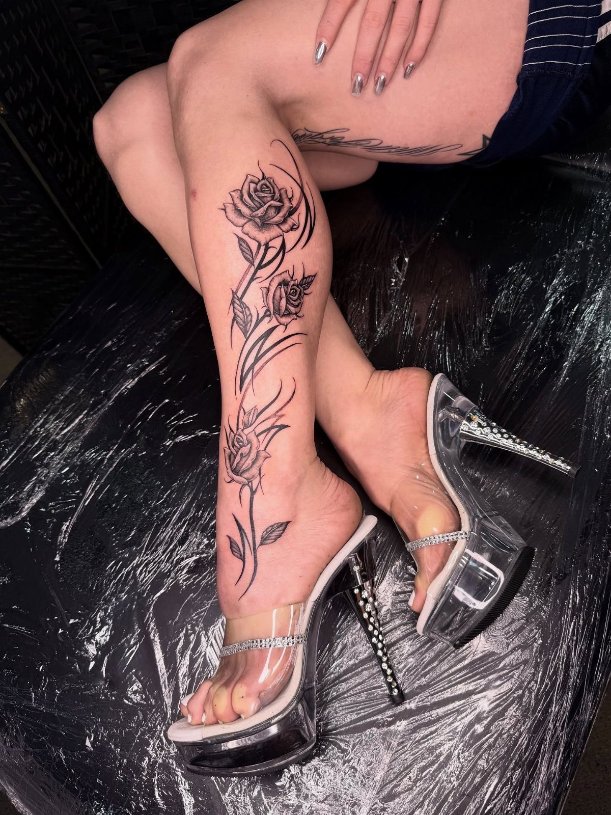 Black ink rose tattoo extending from the ankle up the lower leg