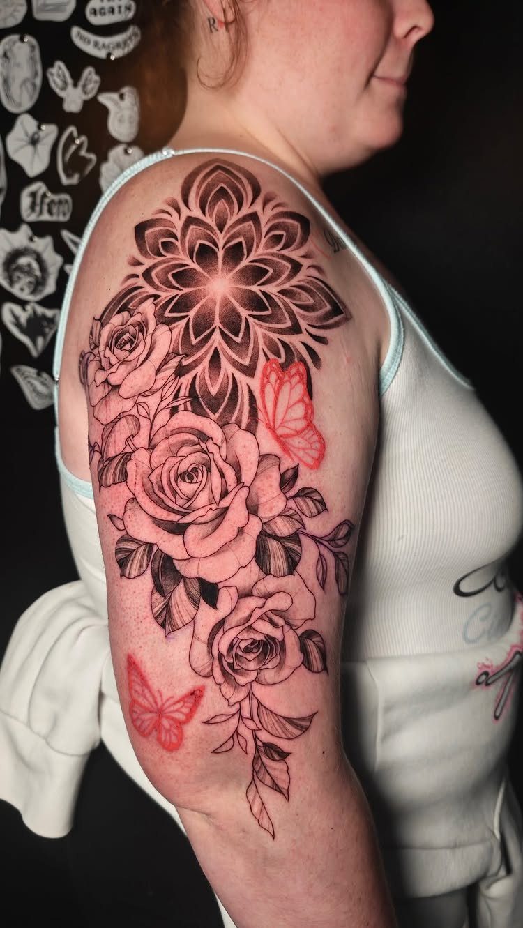 Black ink tattoo of roses and a mandala with red butterflies on an arm