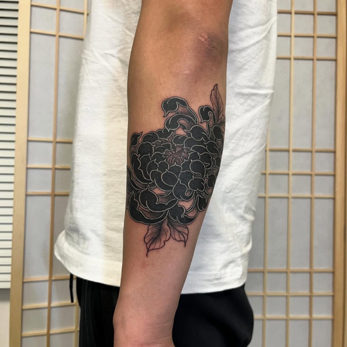 Bold black ink Japanese style rose tattoo on a person's forearm
