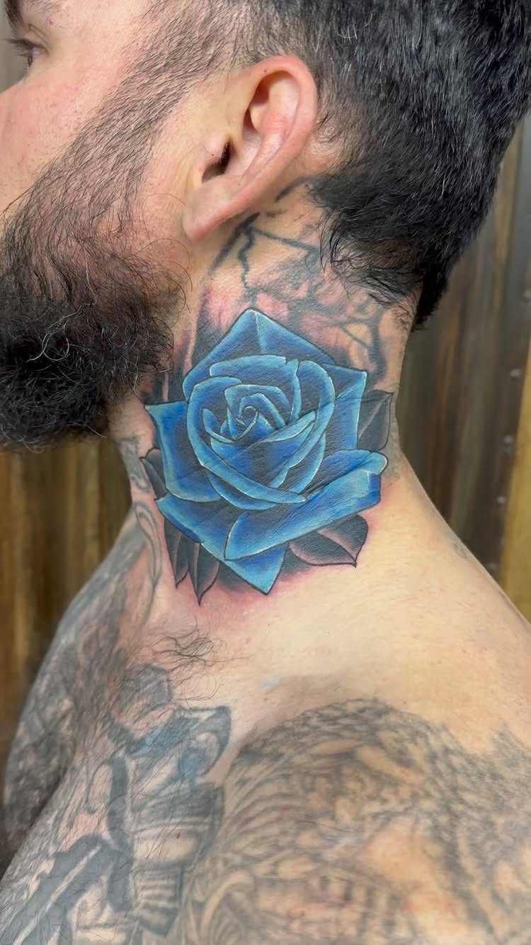 Blue rose tattoo with geometric lines on a man's neck and shoulder.