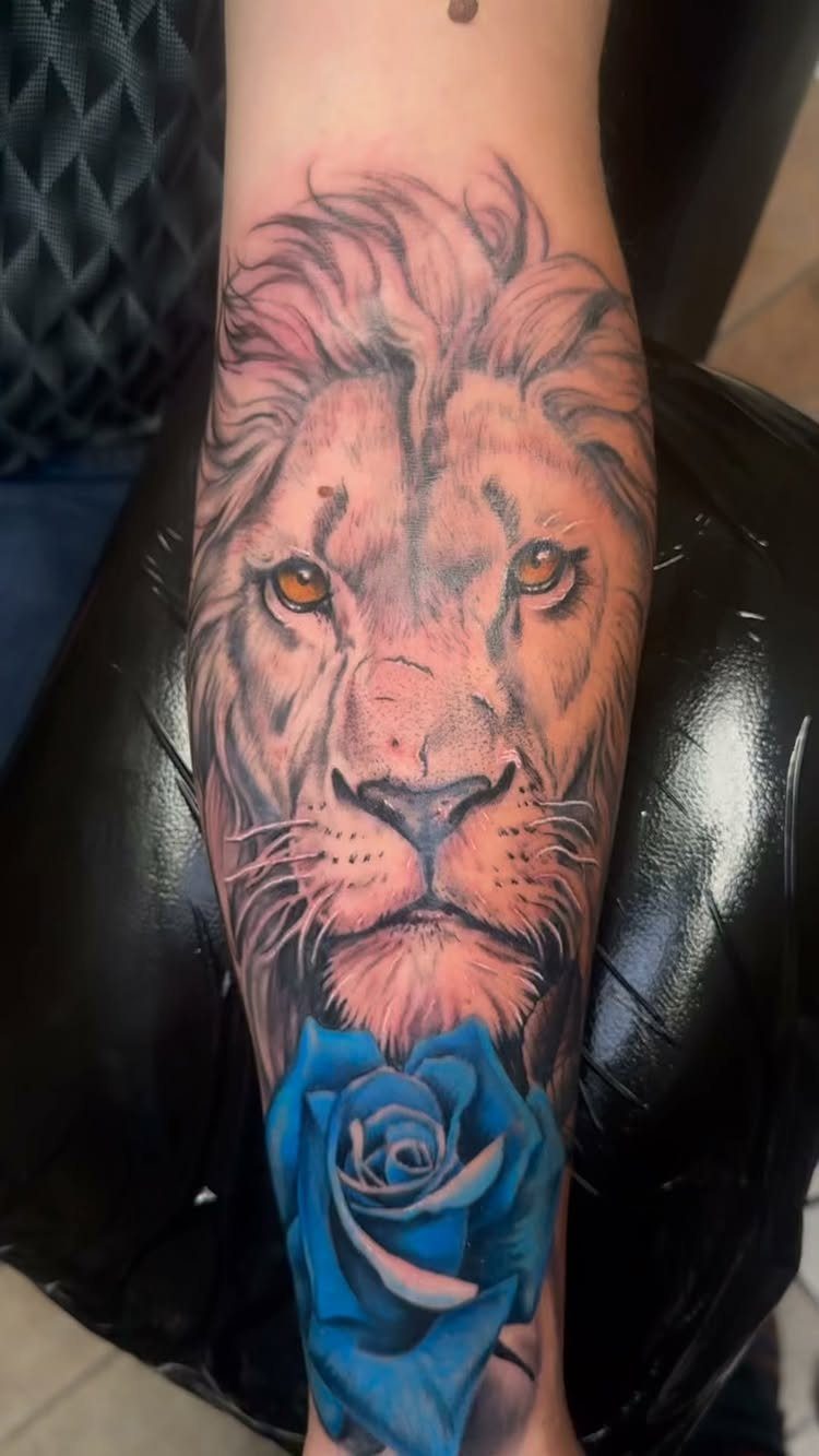 Realistic lion face tattoo with a vibrant blue rose on a forearm
