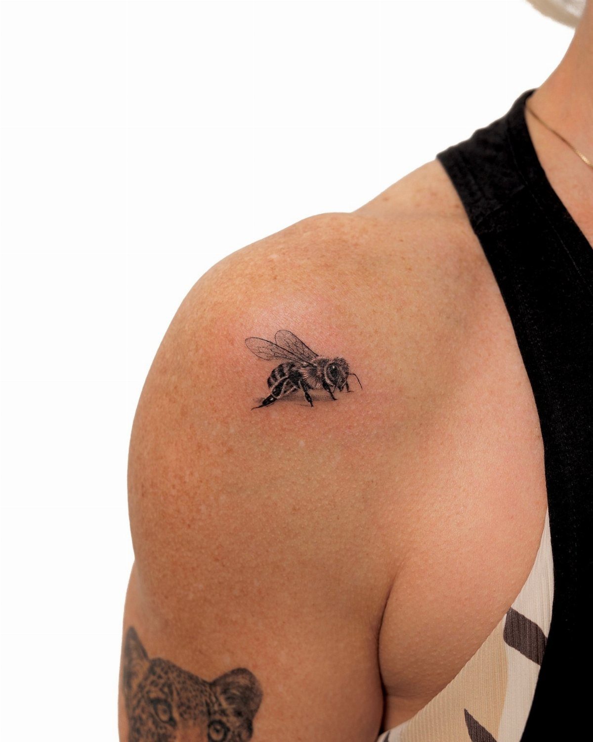 Bumble bee tattoo in flight on a person's shoulder in black and grey ink