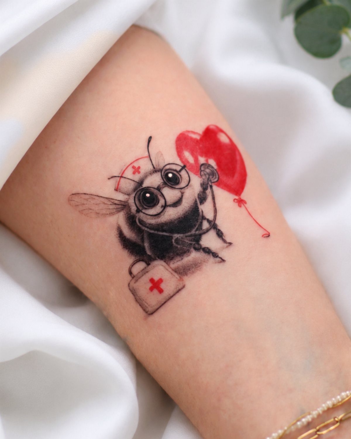 Nurse bumble bee tattoo holding a red heart balloon and a first-aid kit.