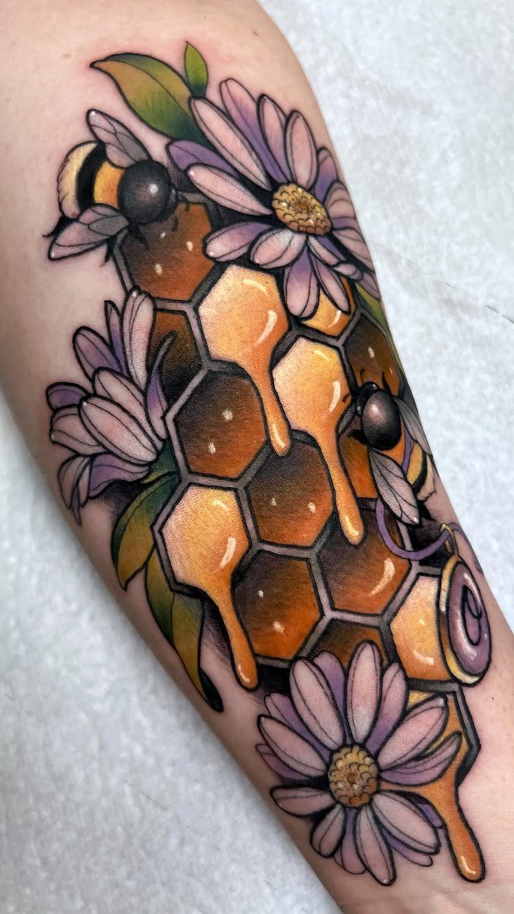 Bumble bee tattoo with golden honeycomb and purple flowers on a person's arm