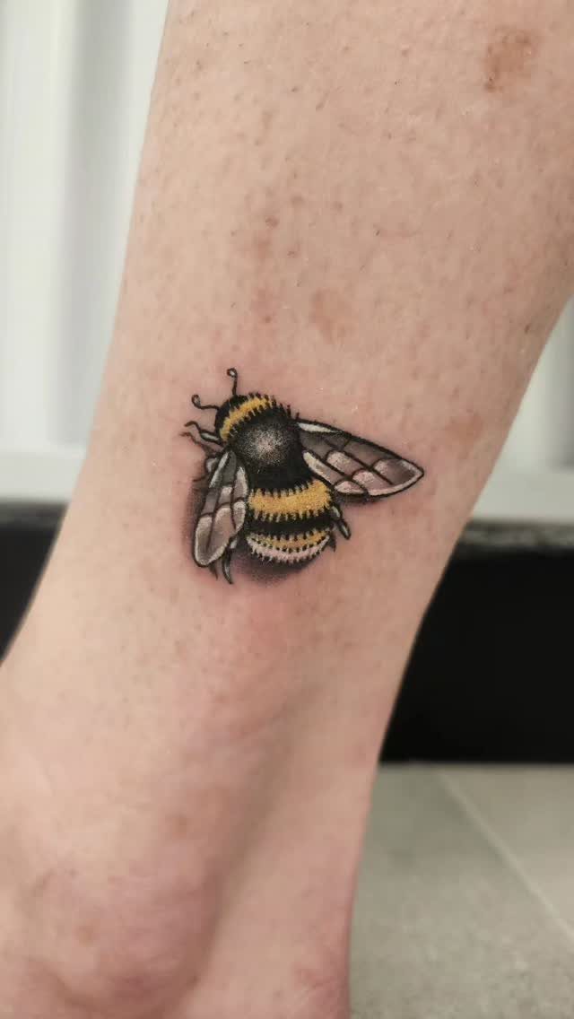 Bumble bee tattoo with realistic yellow and black stripes on human skin.