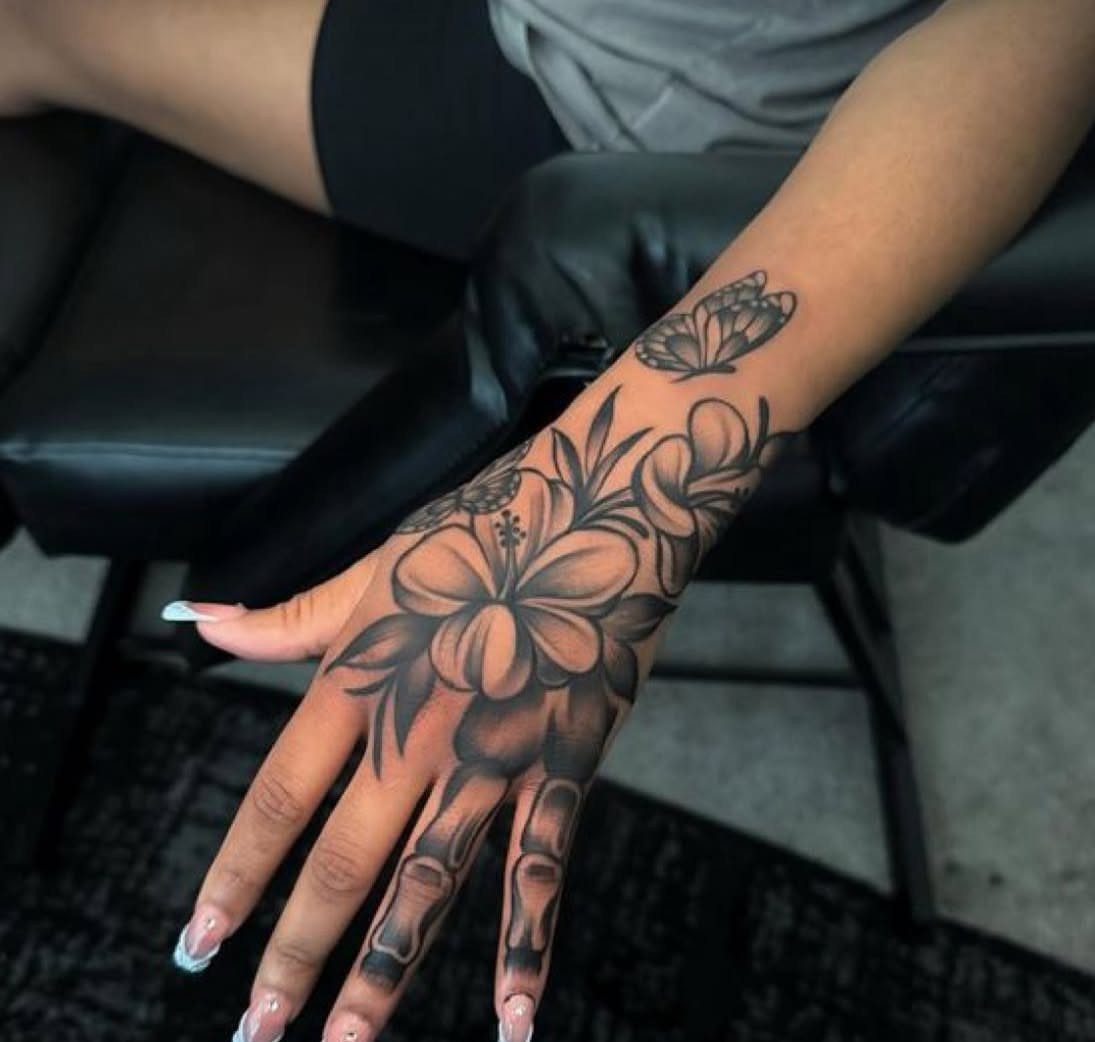 Hand tattoo featuring a butterfly on the wrist and skeletal finger bones.