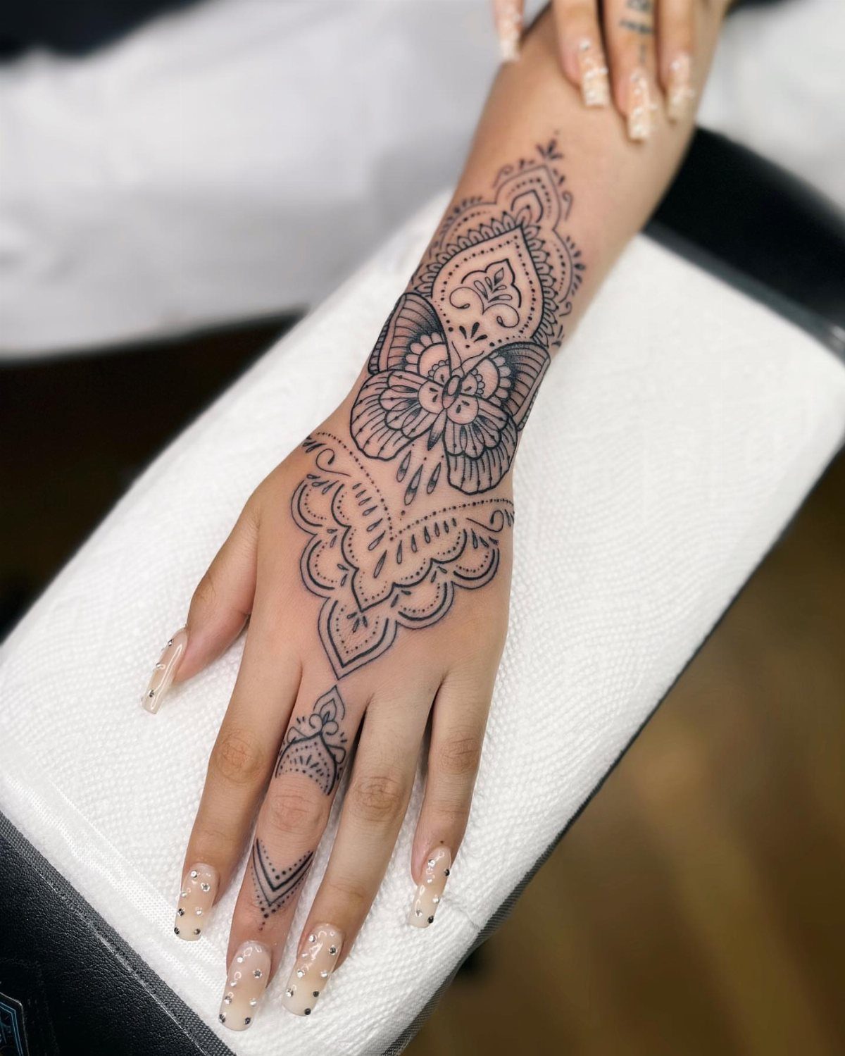 Butterfly hand tattoo with intricate mandala patterns on a person's hand and wrist