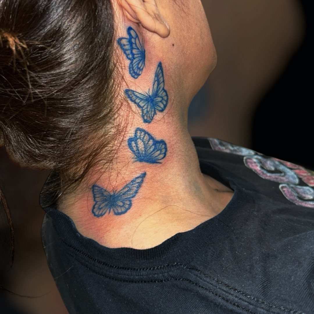 Four blue butterfly tattoos arranged vertically on the side of a person's neck.
