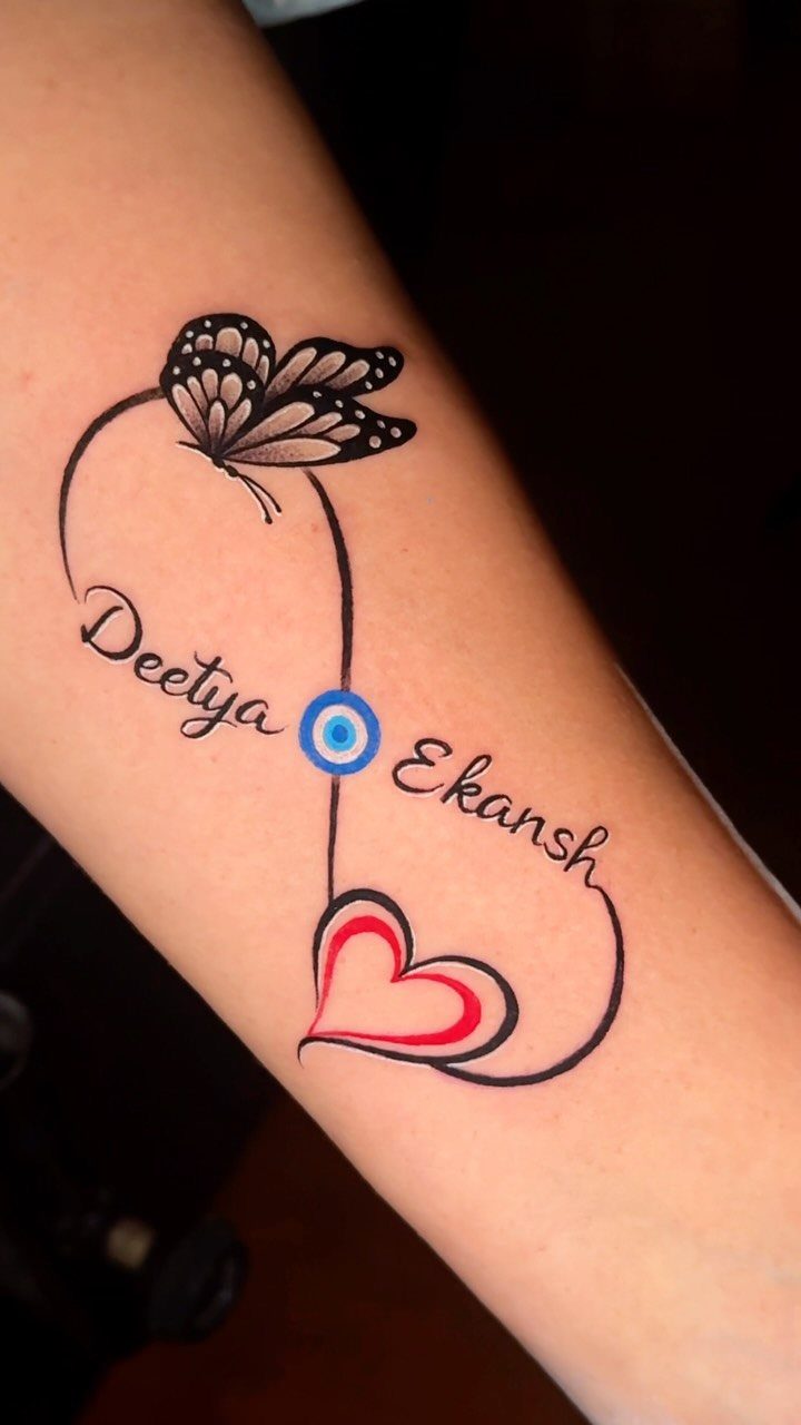 Butterfly tattoo on forearm with infinity symbol, names Deetya and Ekansh, and heart.