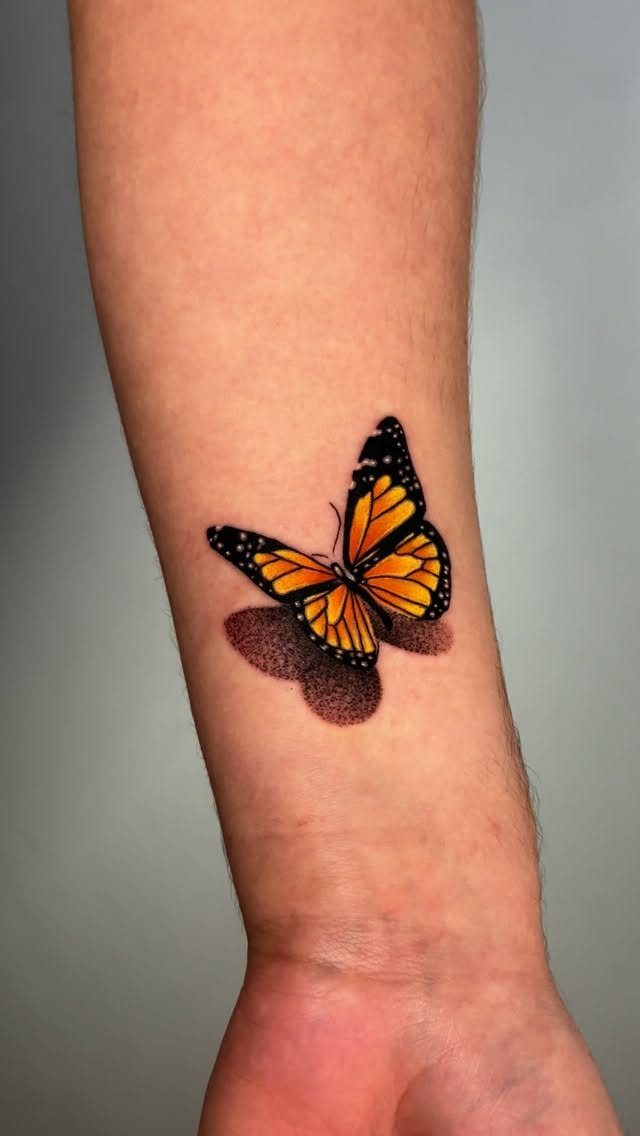 Monarch butterfly tattoo with orange and black wings and a 3D shadow on skin