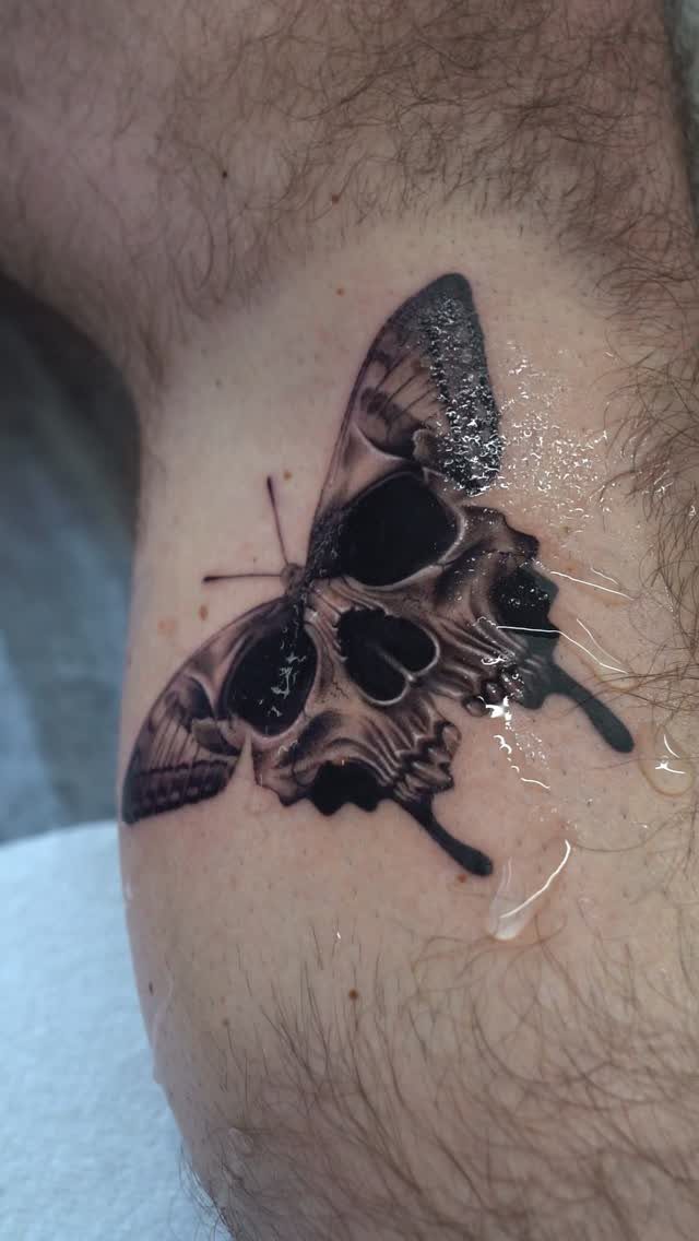 Butterfly tattoo with a human skull integrated into the wings on a leg