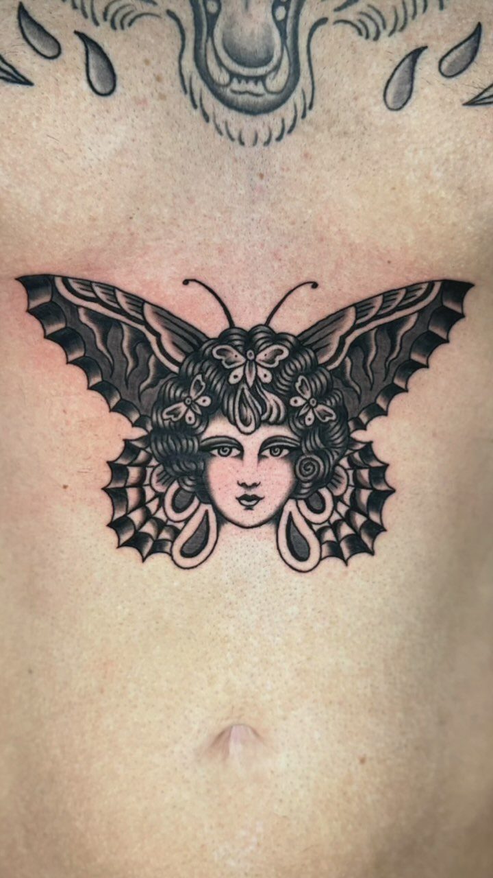 Butterfly tattoo with a woman's face in the center on a person's stomach