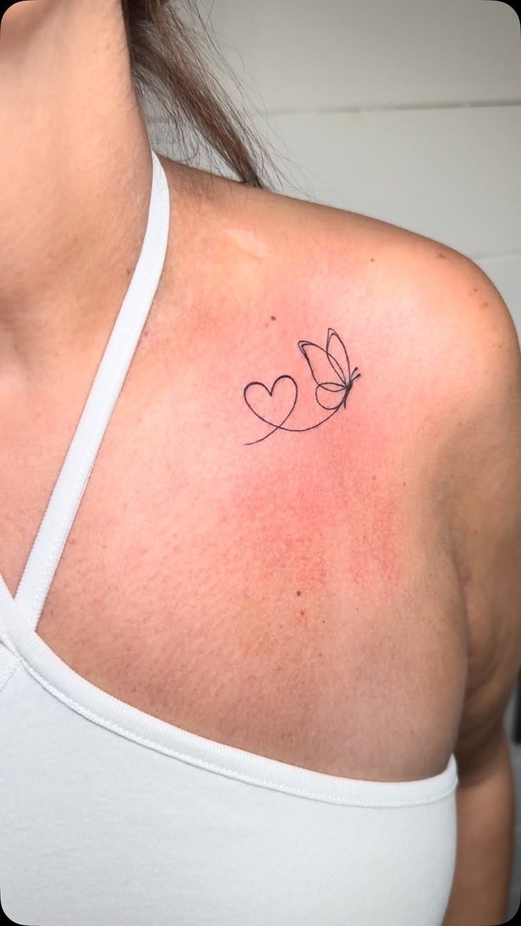 Small butterfly and heart tattoo on a person's shoulder and collarbone area.
