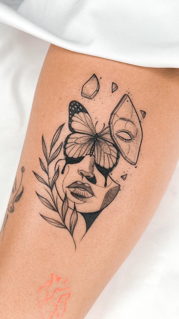 Butterfly tattoo on upper arm featuring a woman's face and geometric shards