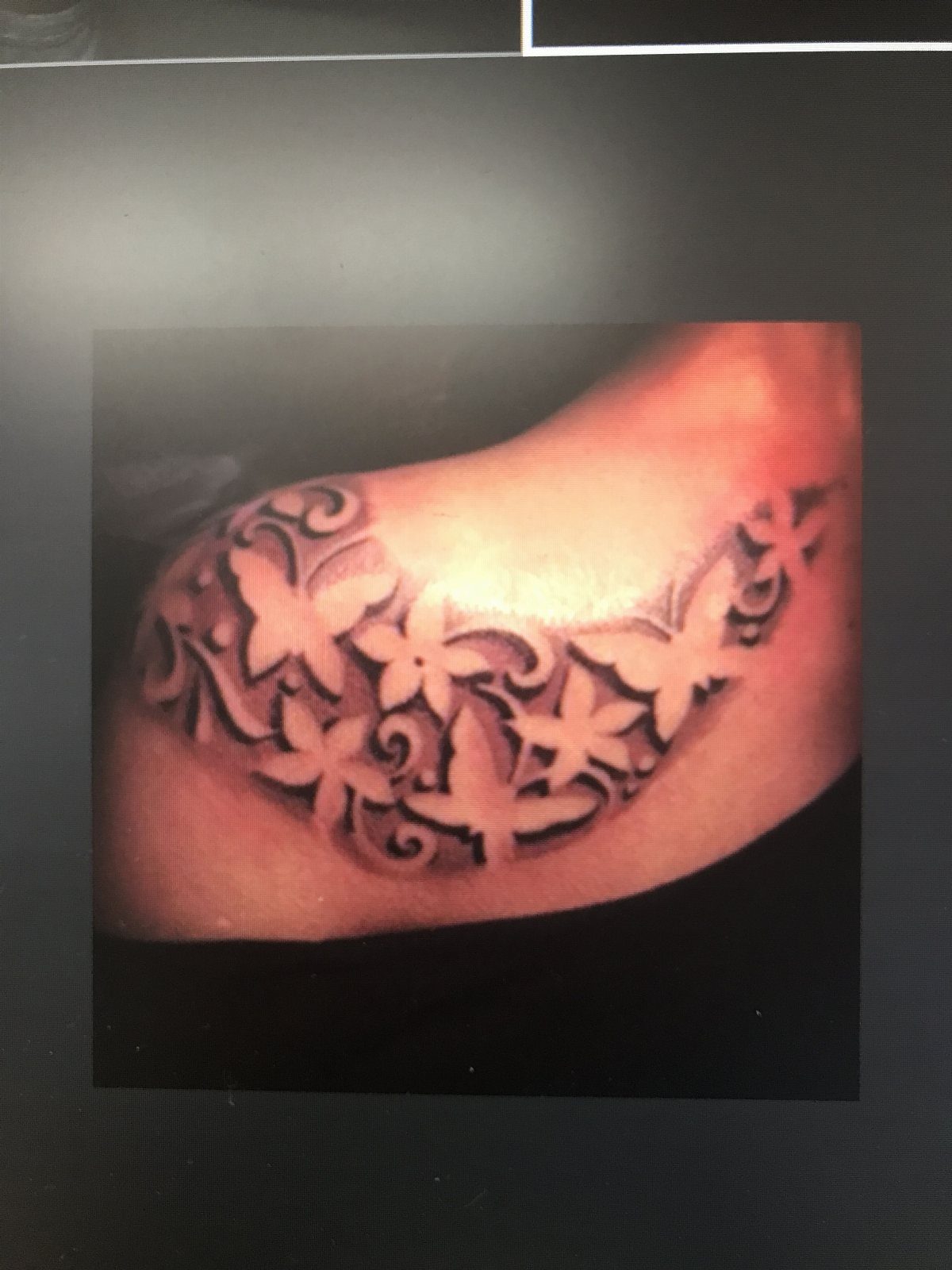 Butterfly and flower tattoo on a shoulder using negative space for the shapes