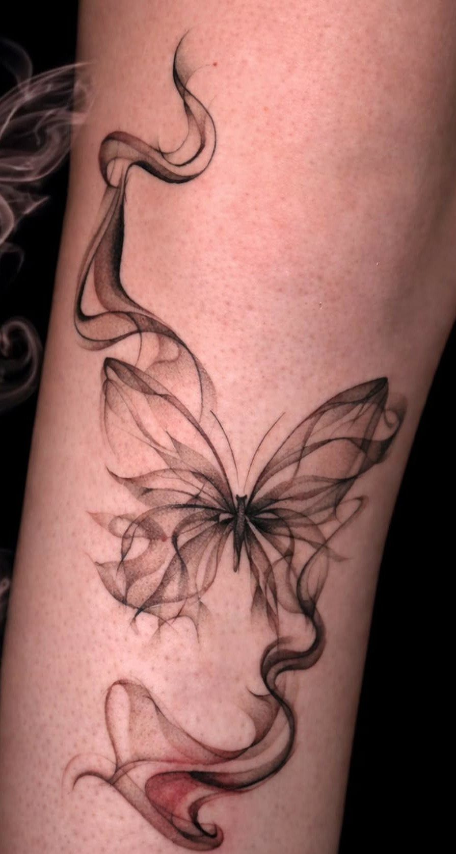 Butterfly tattoo with smoke-like wings and flowing lines on a person's skin