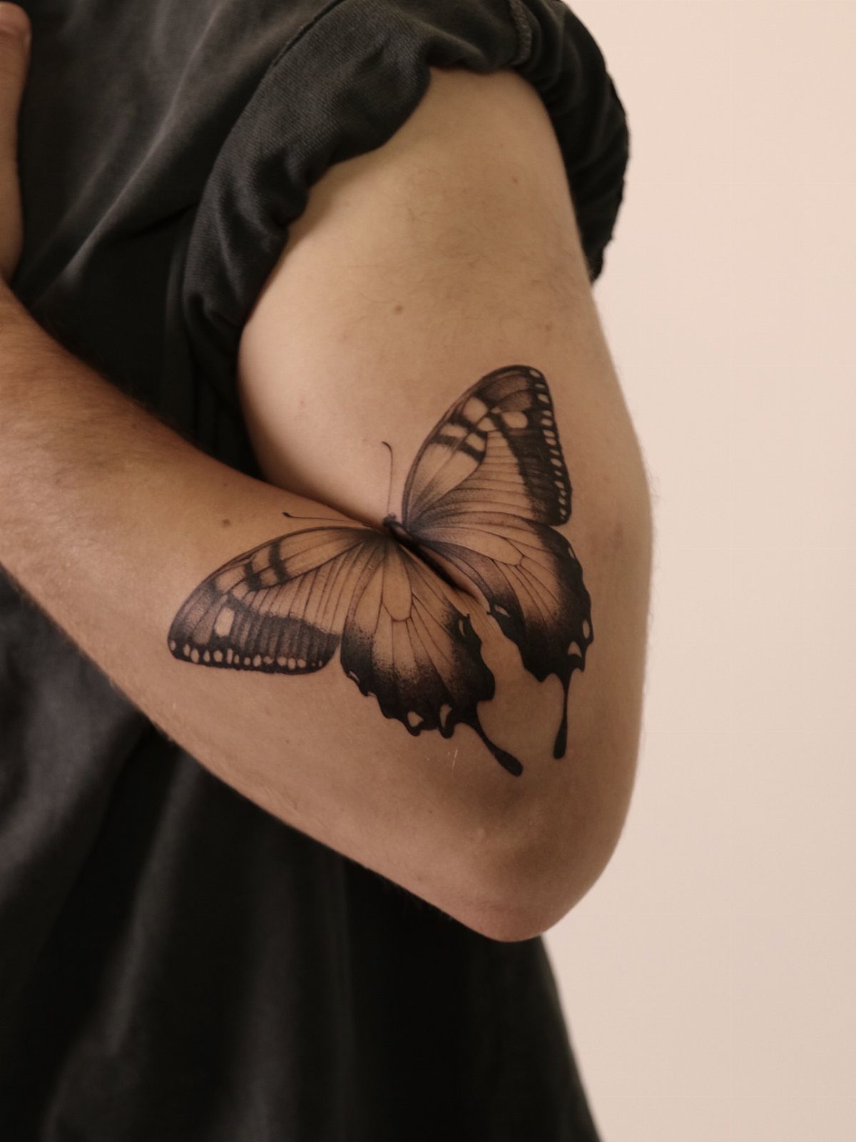 Butterfly tattoo on a shoulder with ink dripping from the bottom of the wings