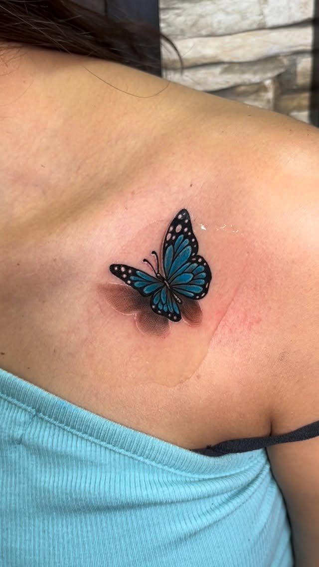 Blue butterfly tattoo on a shoulder with shading for a 3D effect
