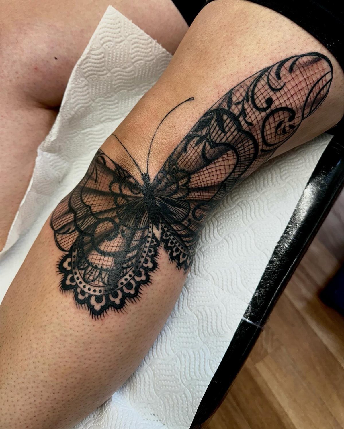 Lace-patterned butterfly tattoo in black ink on a person's forearm