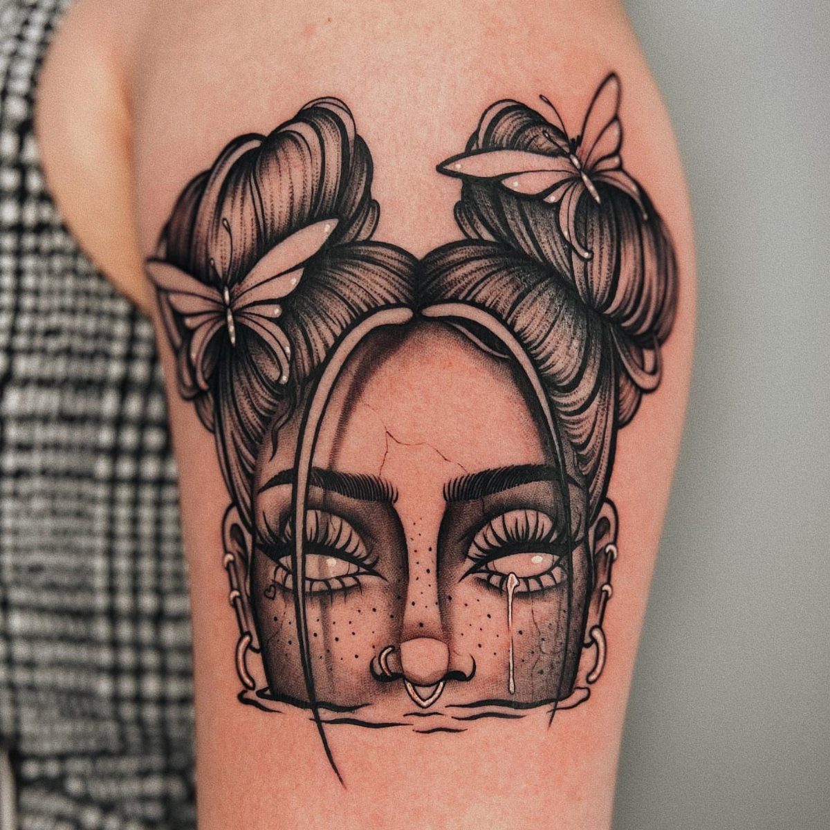 Black and grey tattoo of a woman's face with butterflies in her hair.