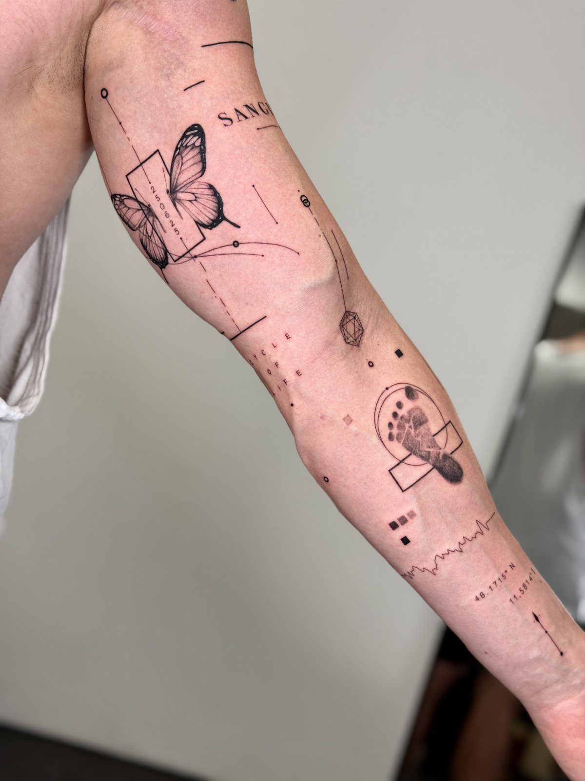 Butterfly tattoo with geometric lines and dots on a person's forearm