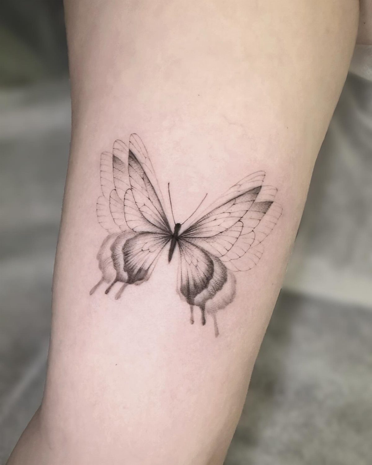 Butterfly tattoo on a forearm with a dripping paint effect on the wings