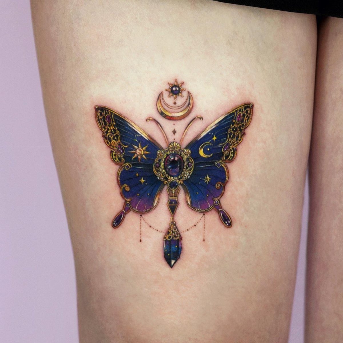Butterfly tattoo with cosmic blue wings, gold details, and a crescent moon.