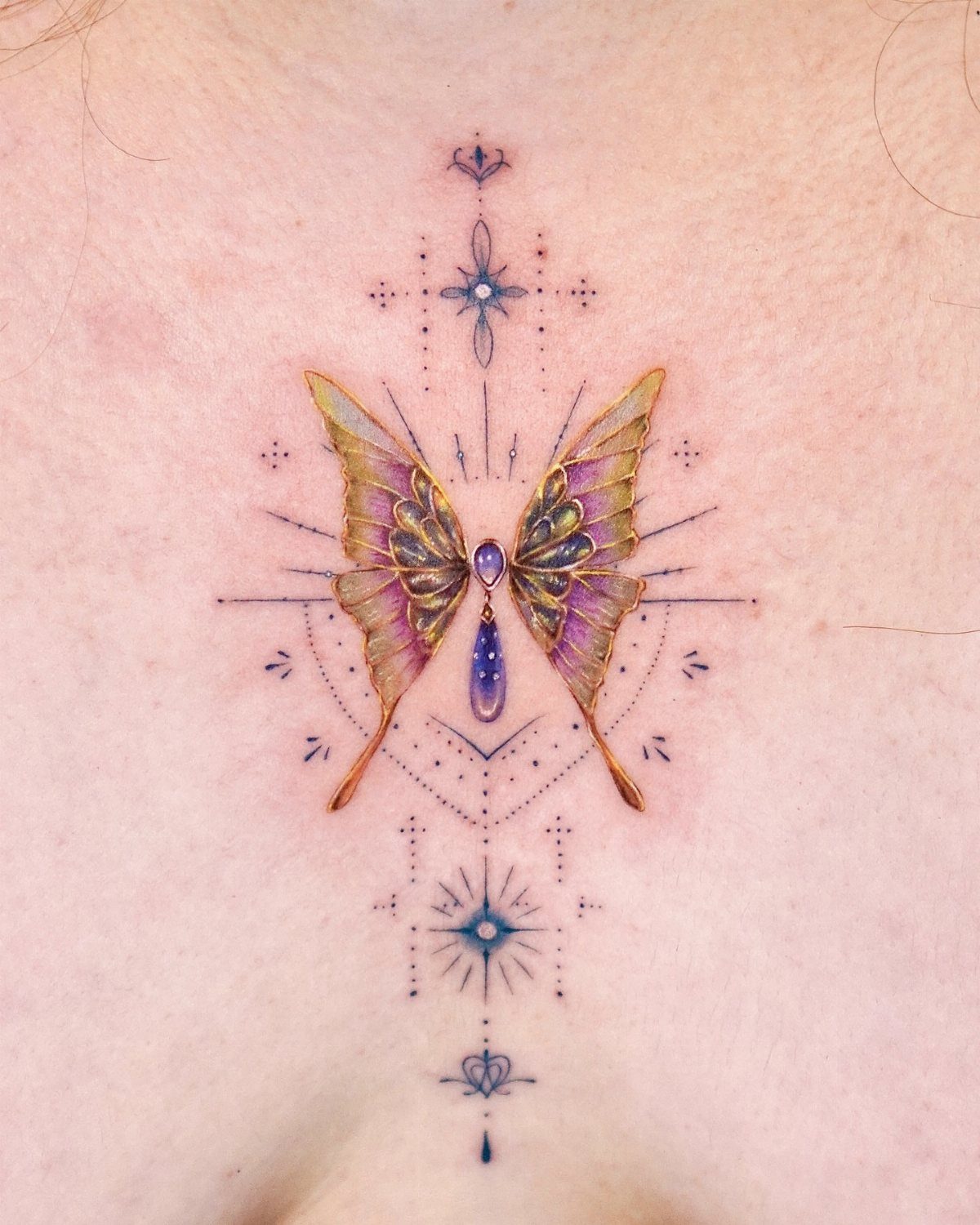 Colorful butterfly tattoo with purple and gold wings and geometric accents on chest