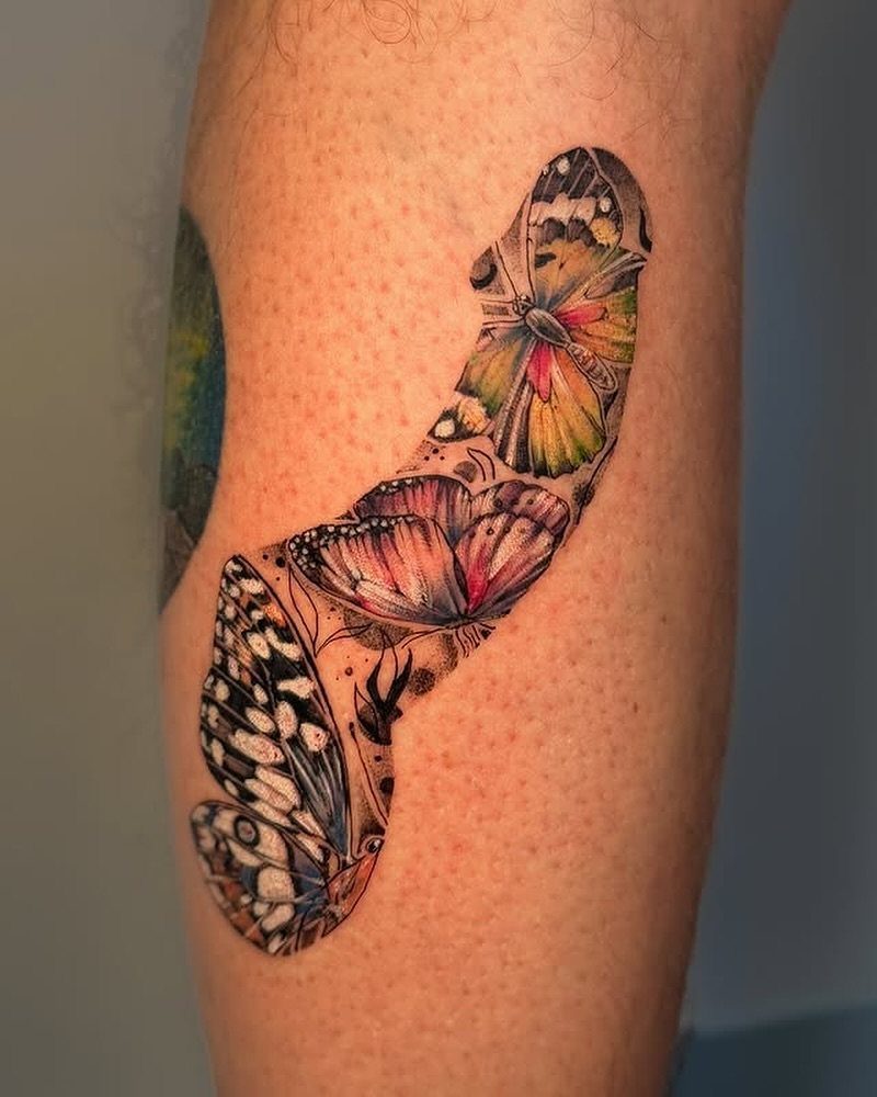 Colorful butterfly and pink flower tattoo on the side of a person's thigh