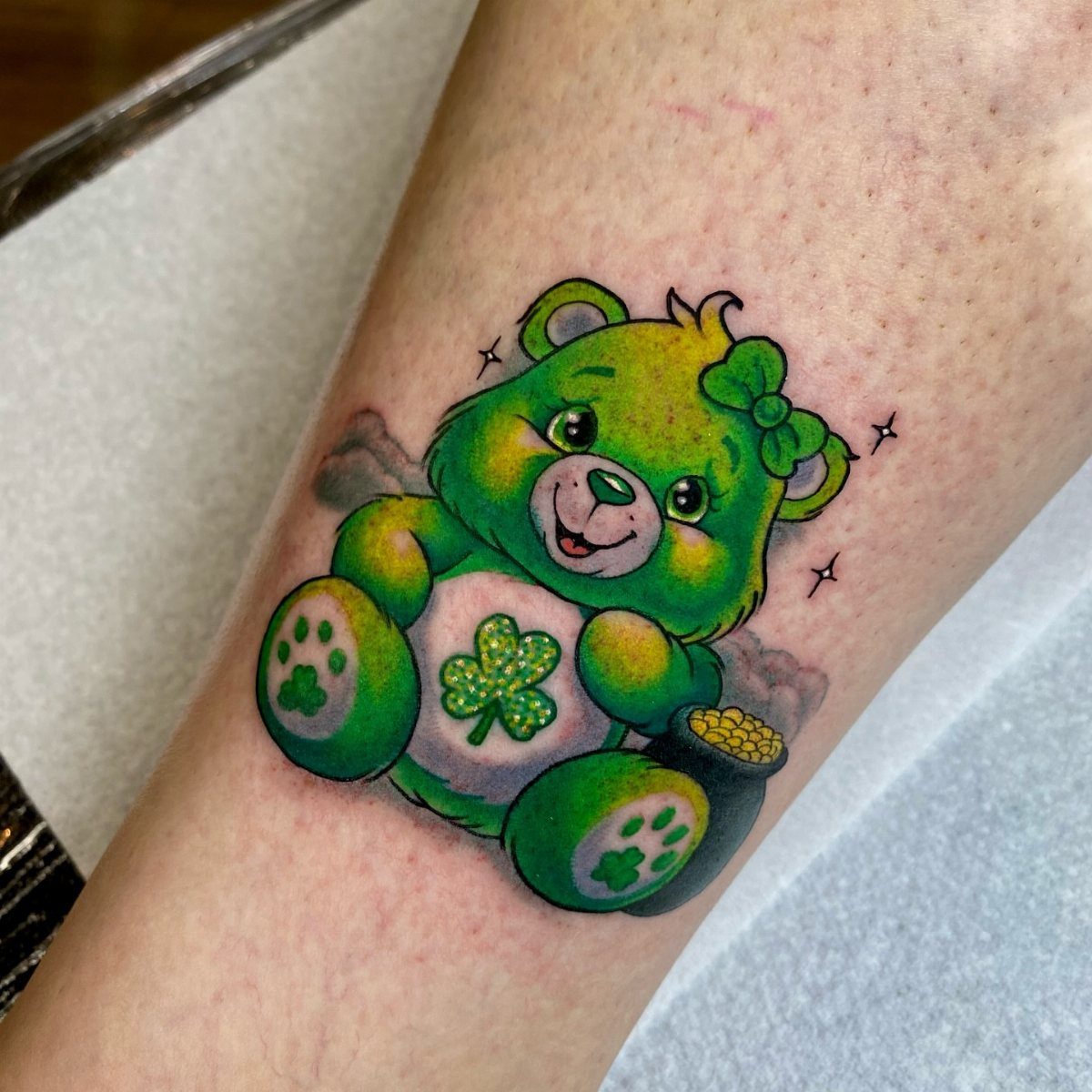Green Lucky Bear tattoo with a four-leaf clover and pot of gold coins.