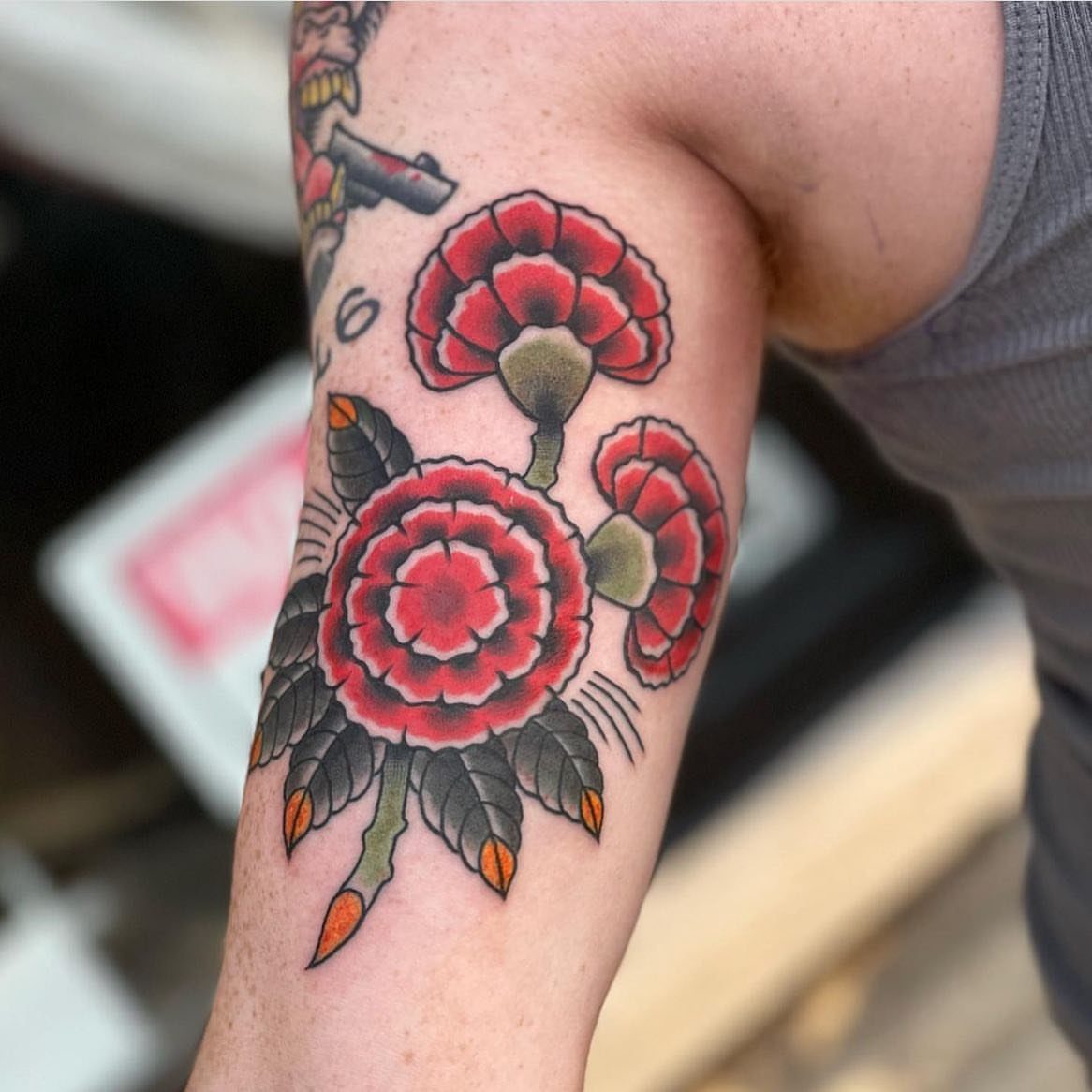 Red carnation flower tattoo in American traditional style on a person's forearm