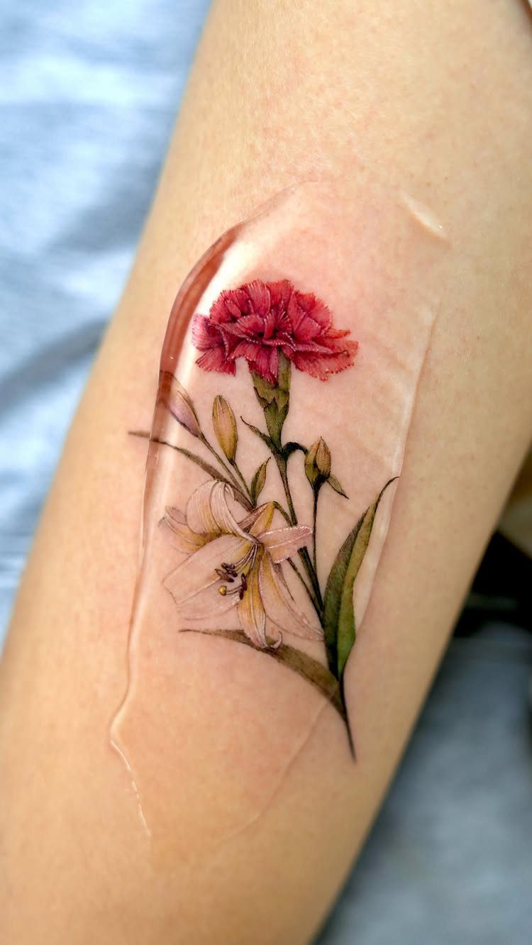Realistic red carnation and white lily tattoo on an arm under protective film