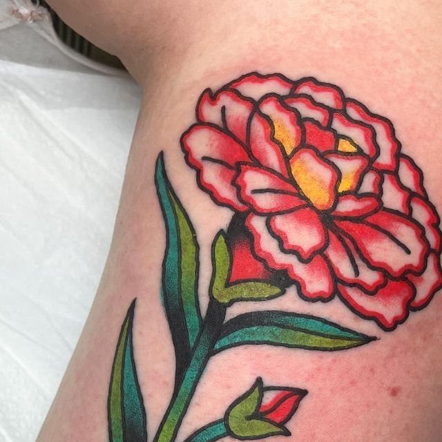 Red and yellow carnation tattoo with bold black outlines on human skin