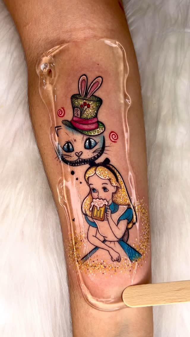Alice and Cheshire Cat tattoo on a forearm with clear gel applied over it