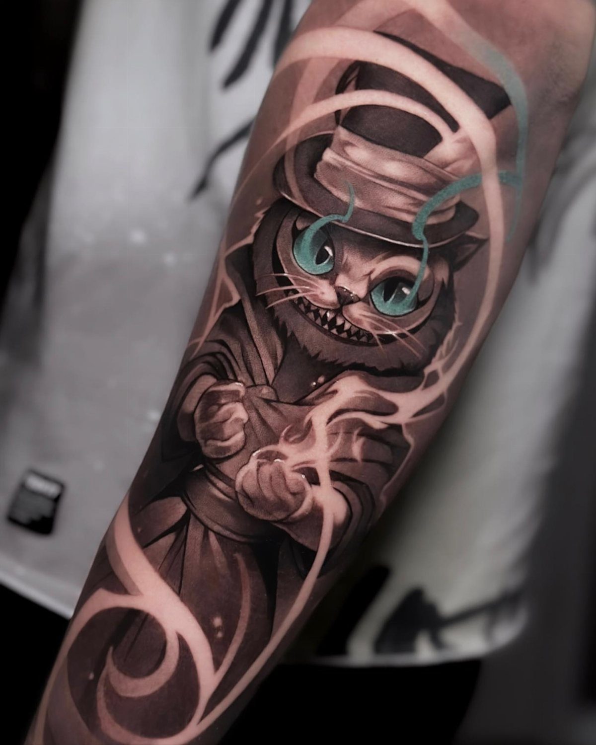 Cheshire Cat tattoo wearing a top hat on a person's forearm