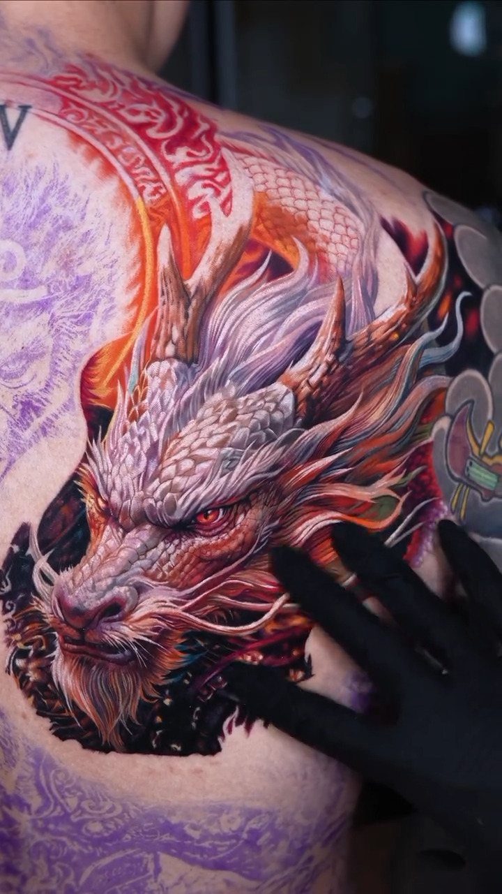 Detailed Chinese dragon tattoo on a person's back with vibrant red and orange colors.