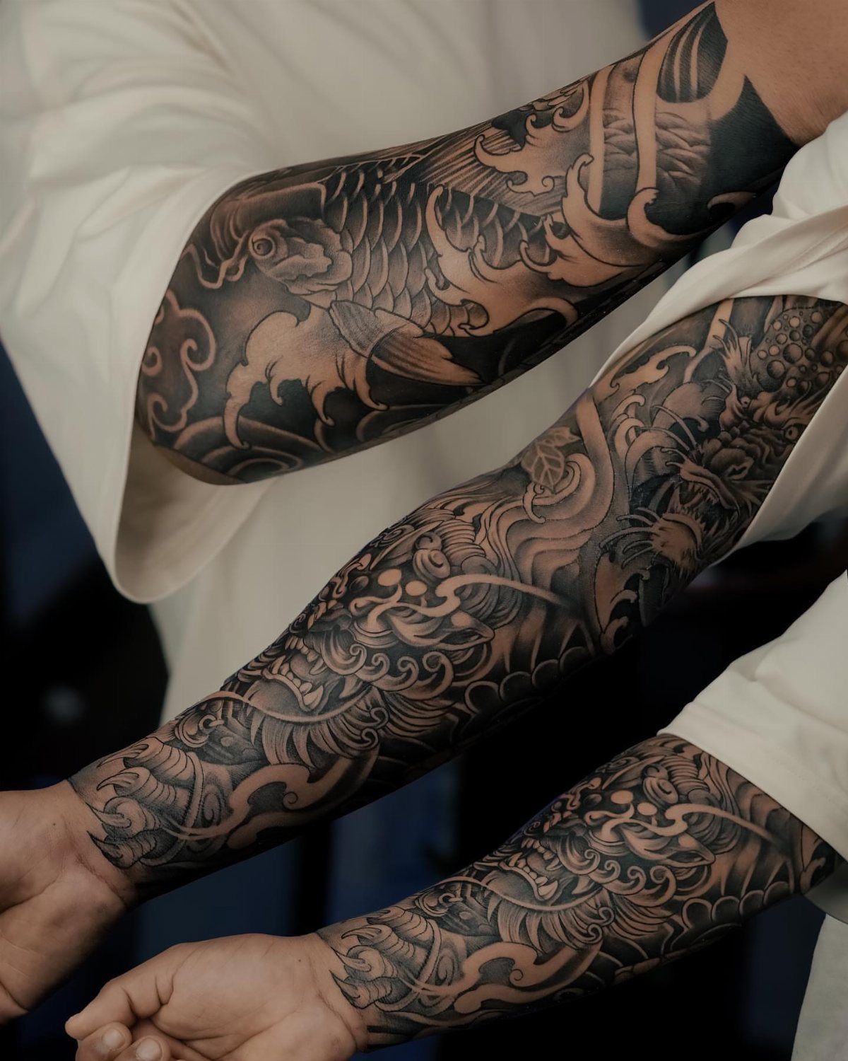 Detailed black and grey Chinese dragon sleeve tattoo wrapping around a person's forearm.