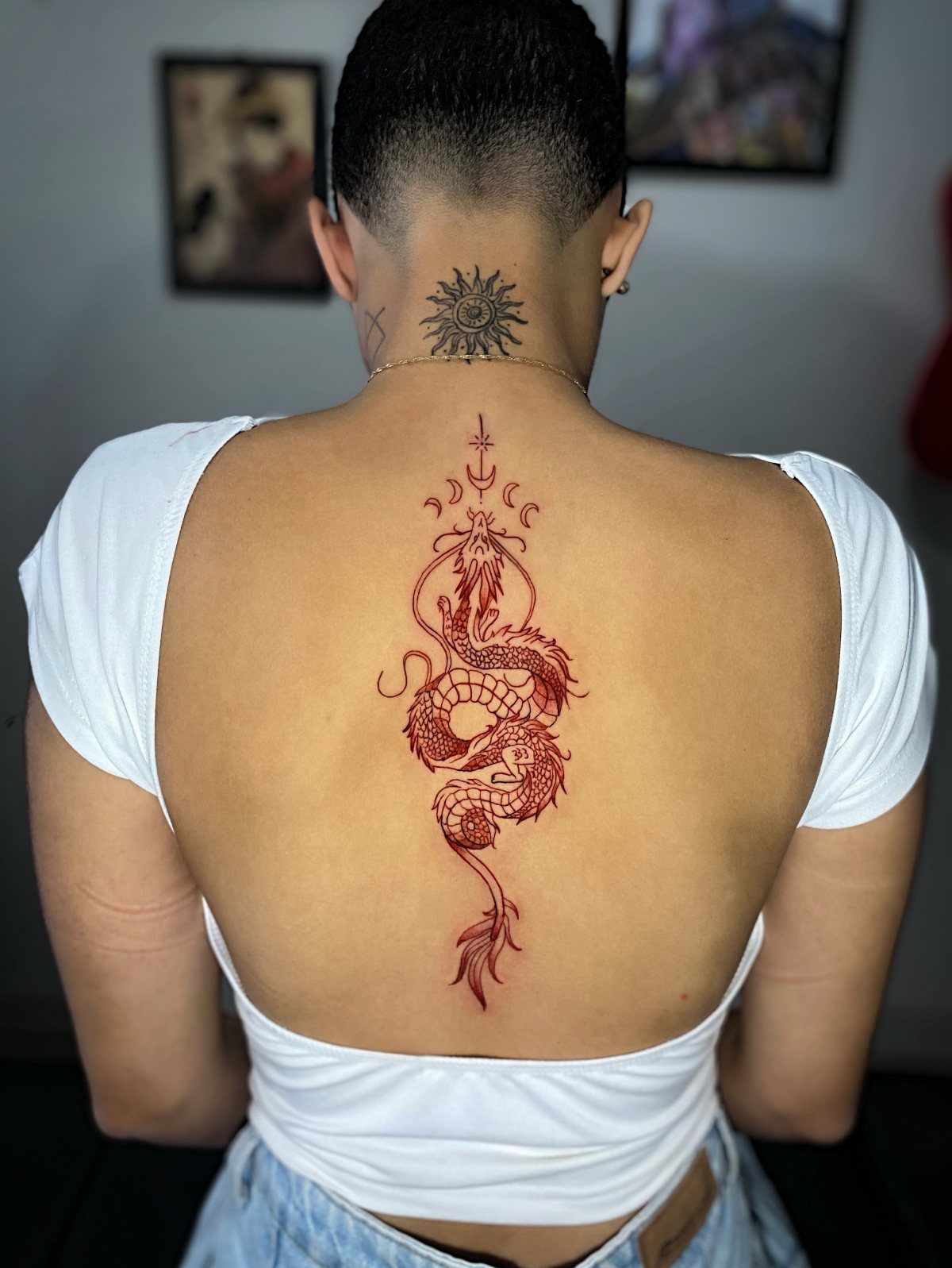 Red Chinese dragon tattoo running vertically down the spine of a person's back
