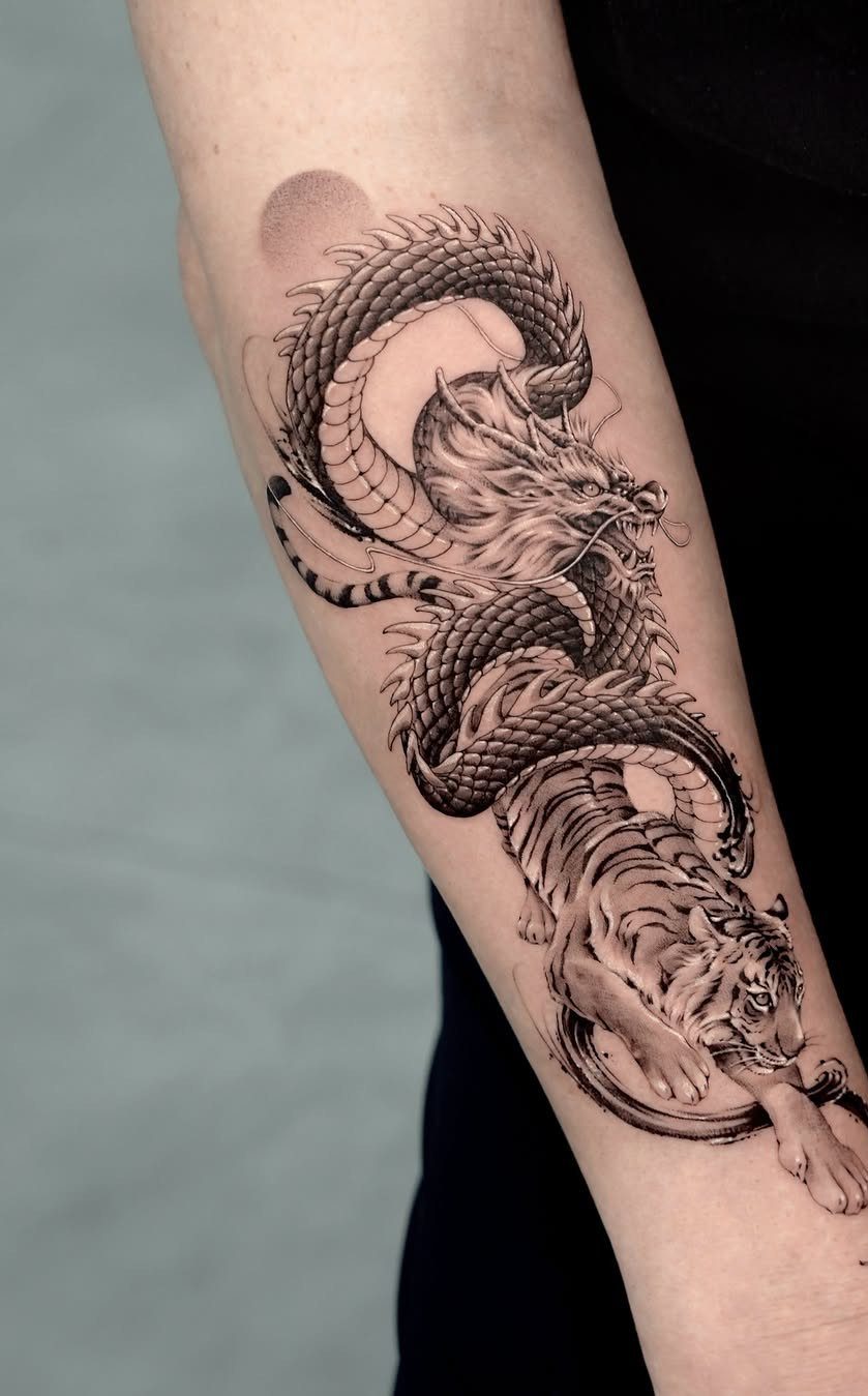 Chinese dragon and tiger tattoo in black and grey ink on a forearm