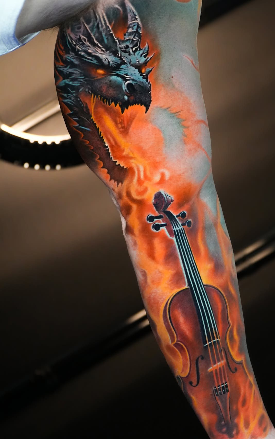 Dragon and violin sleeve tattoo surrounded by bright orange and yellow flames