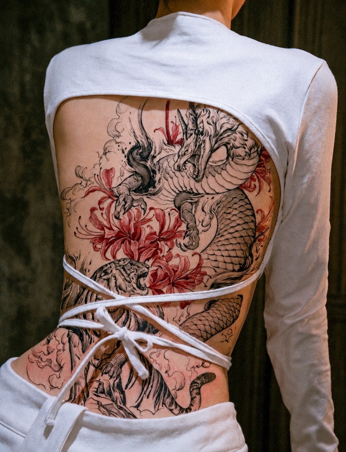 Dragon and tiger tattoo on a person's back with red floral accents