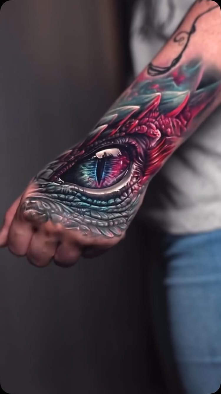 Realistic dragon eye tattoo with colorful scales on a person's forearm and hand
