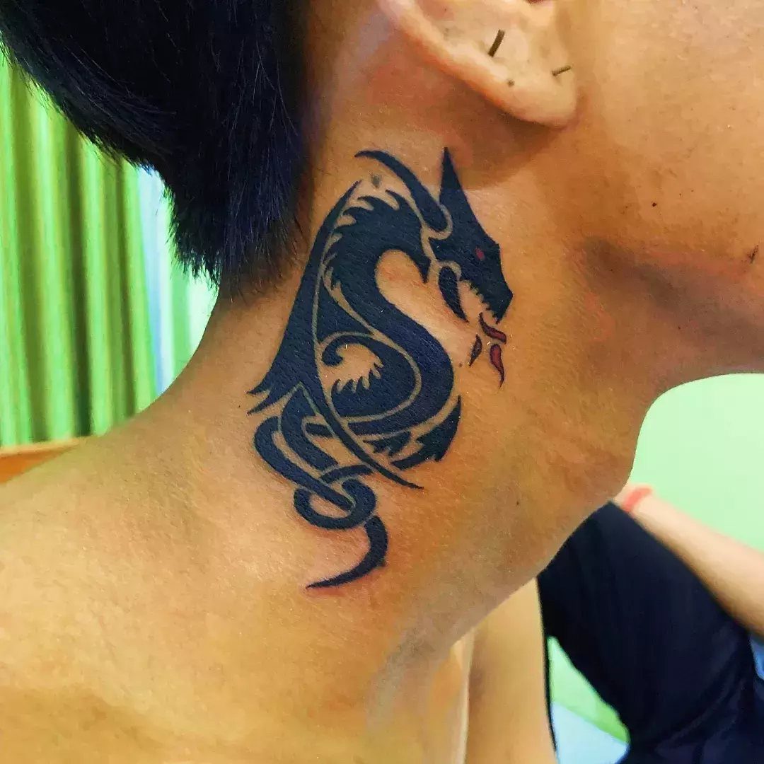 Tribal dragon tattoo with bold black swirling lines on a person's neck