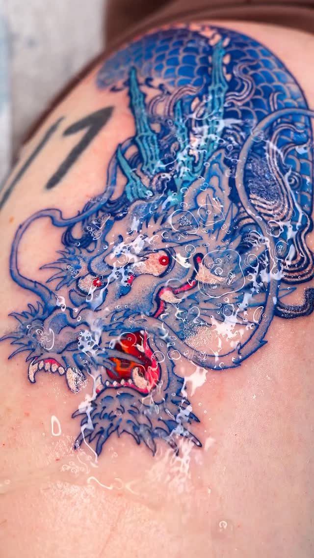 Blue dragon head tattoo with red eyes on skin covered in ointment