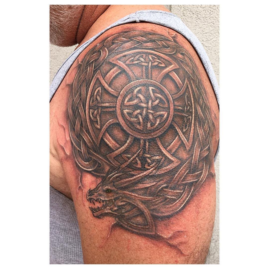 Celtic dragon tattoo on a man's shoulder with intricate knotwork and dragon head.