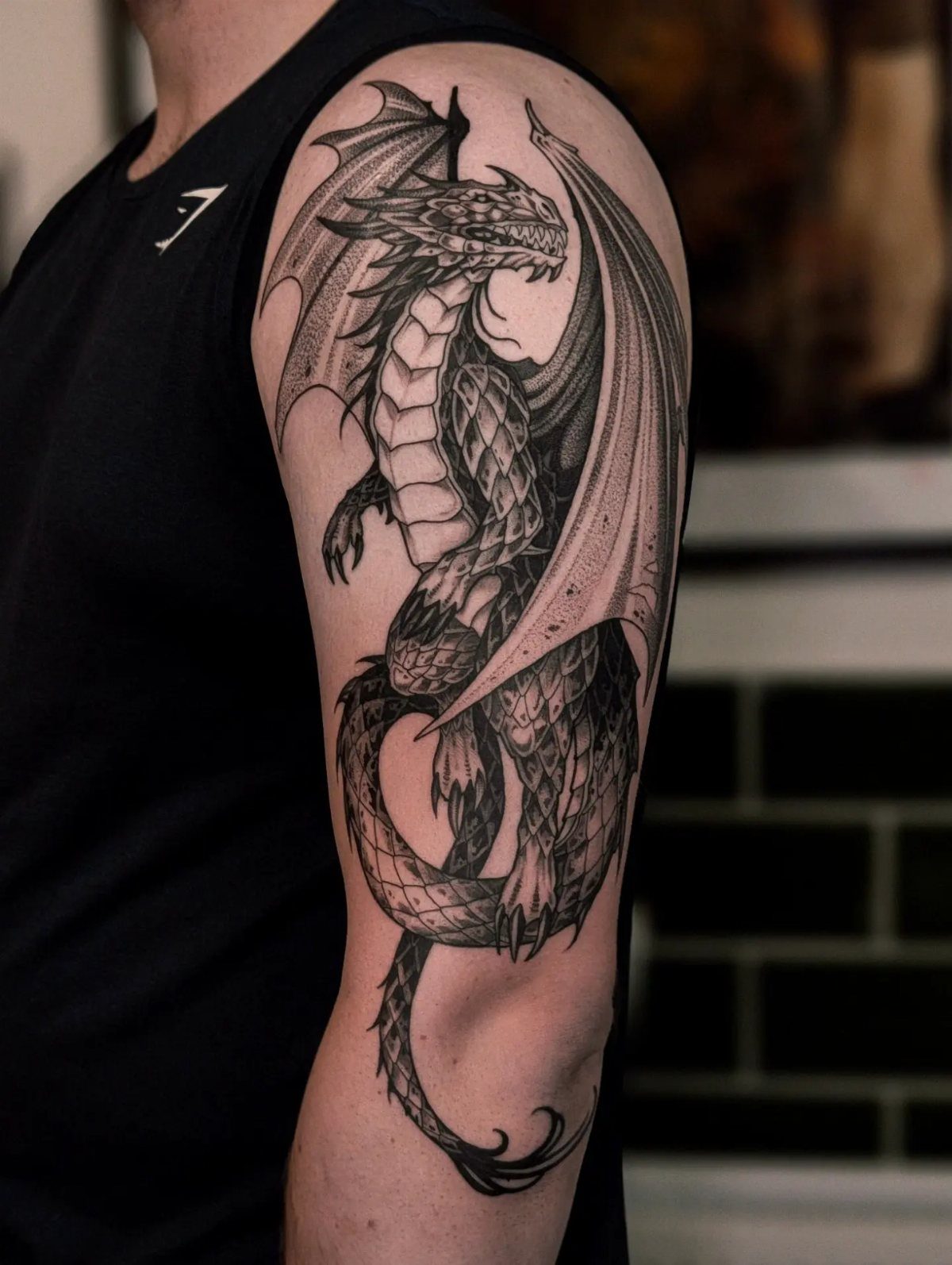 Detailed black ink dragon tattoo on a man's upper arm and shoulder